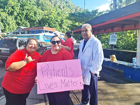 Nurses with sign as doctor looks on