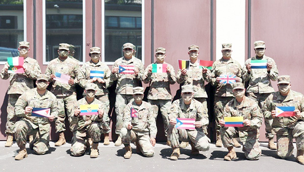 Diverse members of 773rd Civil Support Team, wih flags of their countries of origin.