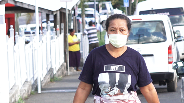 A woman walking on the street in Apia wearing a mask
