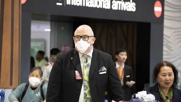 Travellers wearing face masks exit the arrivals hall at Auckland International Airport