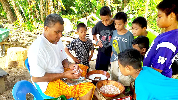 Youngsters watch as palusami is prepared for the umu