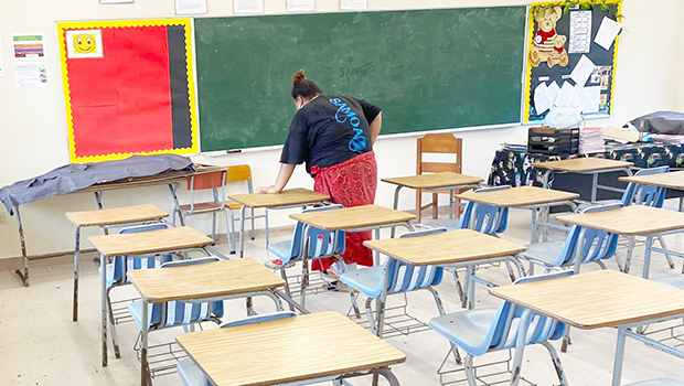 A DOE employee cleaning a classroom