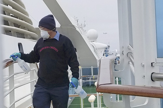 A cruise ship worker cleans a railing on the Grand Princess 