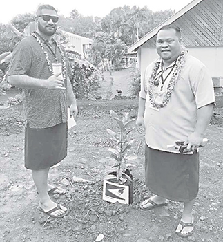  AS-EPA deputy director William Sili and AS-EPA finance and special projects manager, Victor Tuiasosopo next to a plant with a photo of the American Samoa flag.
