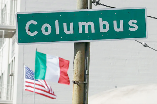 Street sign that says Columbus with flags in background