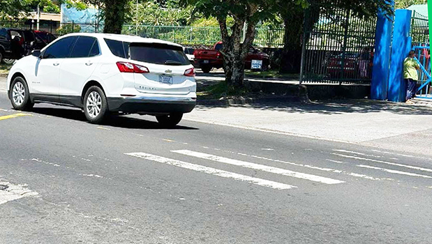 Car passes crosswalk with faded paint