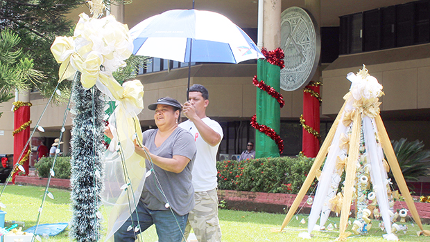 Two ASG employees hang Christmas lights at the EOB