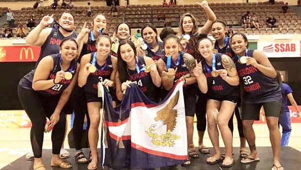 The American Samoa women’s basketball team celebrate atop the podium with their gold medals.
