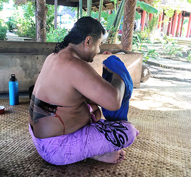 A schoolteacher in the midst of receiving a full pe'a