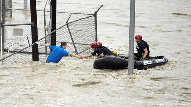 Rescue personnel grab the the hand of a man stranded in rushing water