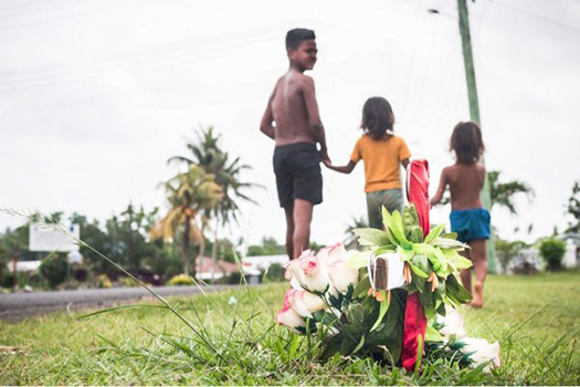 Village children walk past a cross planted at Faleula 