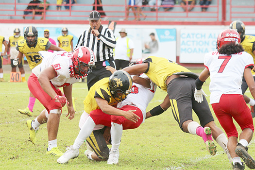 Faga'itua Vikings ball carrier Roy Ulugalu is tackled by two Nu’uuli Wildcat defenders 
