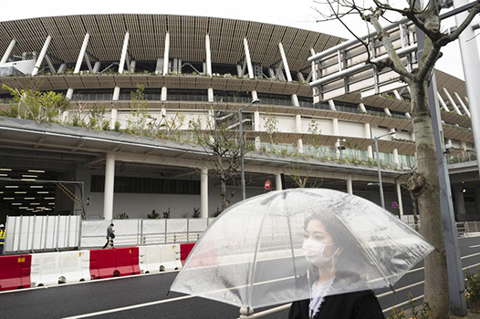A woman walks past the New National Stadium, a venue for the opening and closing ceremonies at the Tokyo 2020 Olympics