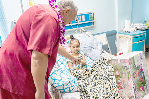 Gov. Lemanu P.S. Mauga delivering gift to a child patient at LBJ