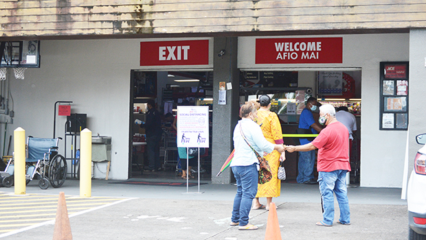 People lining up waiting to get into a store with social distancing inforced