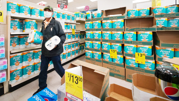 A masked customer grabs two packages of toilet paper at Longs Drugs in Moiliili.