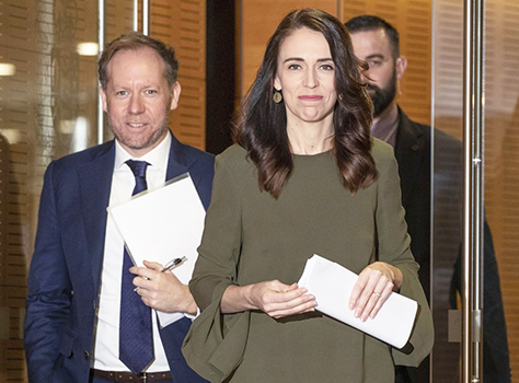 New Zealand Prime Minister Jacinda Ardern with two men in the background