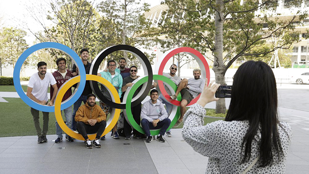 A group of students from Uruguay pose for a souvenir picture on the Olympic Rings set outside the Olympic Stadium in Tokyo