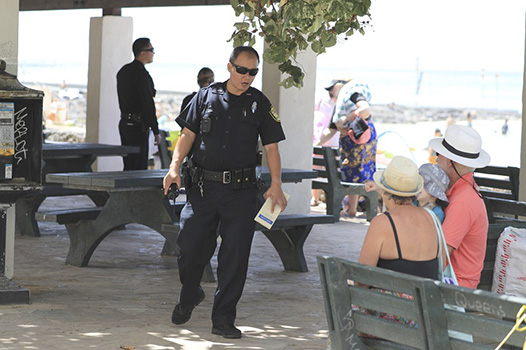 Honolulu police officer telling a couple the beach is closed.