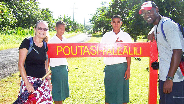 Peace Corps volunteers infron of Poutasi Village sign 