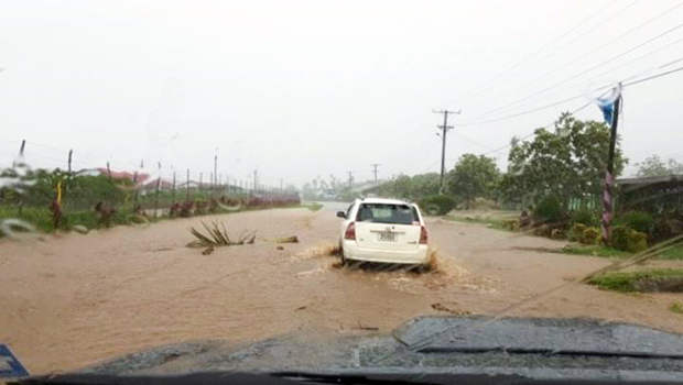 The flooded road at Satapuala, Samoa with cars attempting to drive through