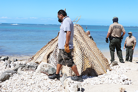 Saute Sapolu looking out from behind his fale as Honolulu cops dismantle it.