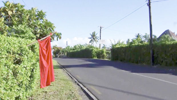 Empty street in Apia with red flag outside a yard.