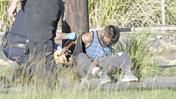 robbery suspect sitting in grass being handcuffed
