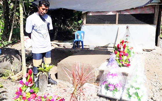 Tu'ivale Luamanuvae beside the graves of his three children