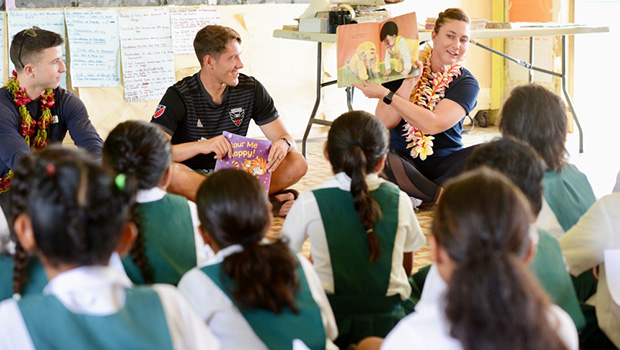 Seaman Eli Teagle, Ensign Landon Klopfenstien, and Ensign Cecelia Hosley read to students at LufiLufi Primary School 
