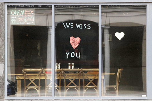 Sign in the window of empty cafe saying, "We miss you"