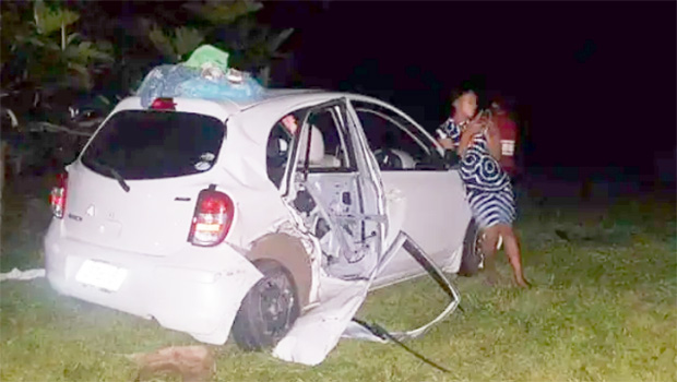 Person leans against front of wrecked white car