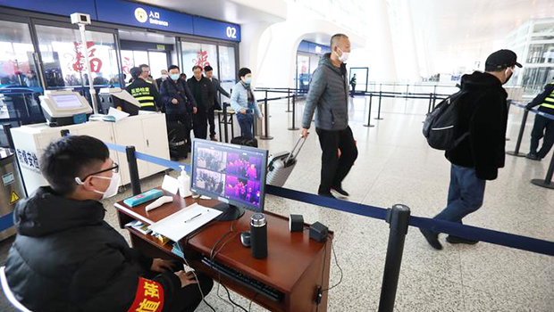 Staff members take passengers' body temperature at Tianhe International Airport in Wuhan