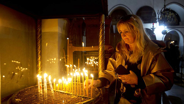 A visitor lights a candle at the Church of the Nativity built