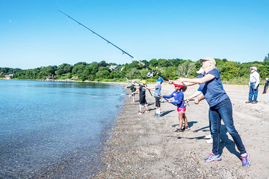 Janet Coit casts her line into the water with others in background