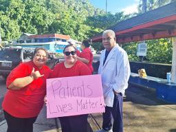 Nurses with sign as doctor looks on