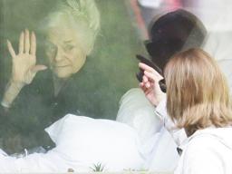 Judie Shape, left, who has tested positive for the coronavirus, waves to her daughter, Lori Spencer