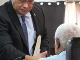 Health director Motusa Tuileama Nua shaking hands with a senator