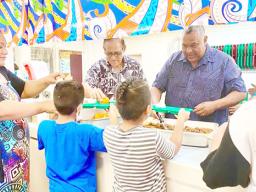 Gov. Lemanu Peleti Palepoi Sialega Mauga serving a line of children lunch