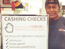 ACE employee beside their check chasing policy sign