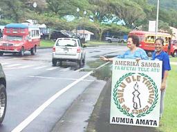 Amata waving behind a thank you sign.  A passerby stops to help out.