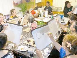 Women painting sitting around a large table