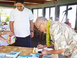 Fuimaono Fini Aitaoto signing the cover of his book