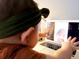 Young cild interacts on woman on a video chat. 