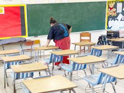 A DOE employee cleaning a classroom
