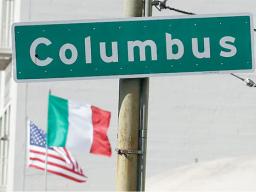 Street sign that says Columbus with flags in background