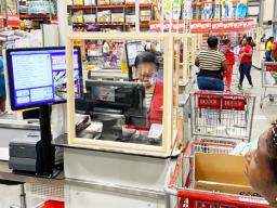 Cost-U-Less checker behind a plexiglass shield.