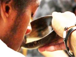 Man takes a sip of kava from the bowl.