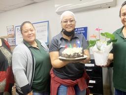 Molly Schuster holding her birthday cake with co-workers