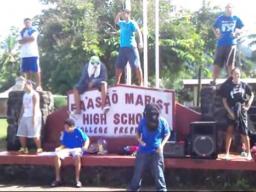 Fa’asao Marist High School sign with students standing near